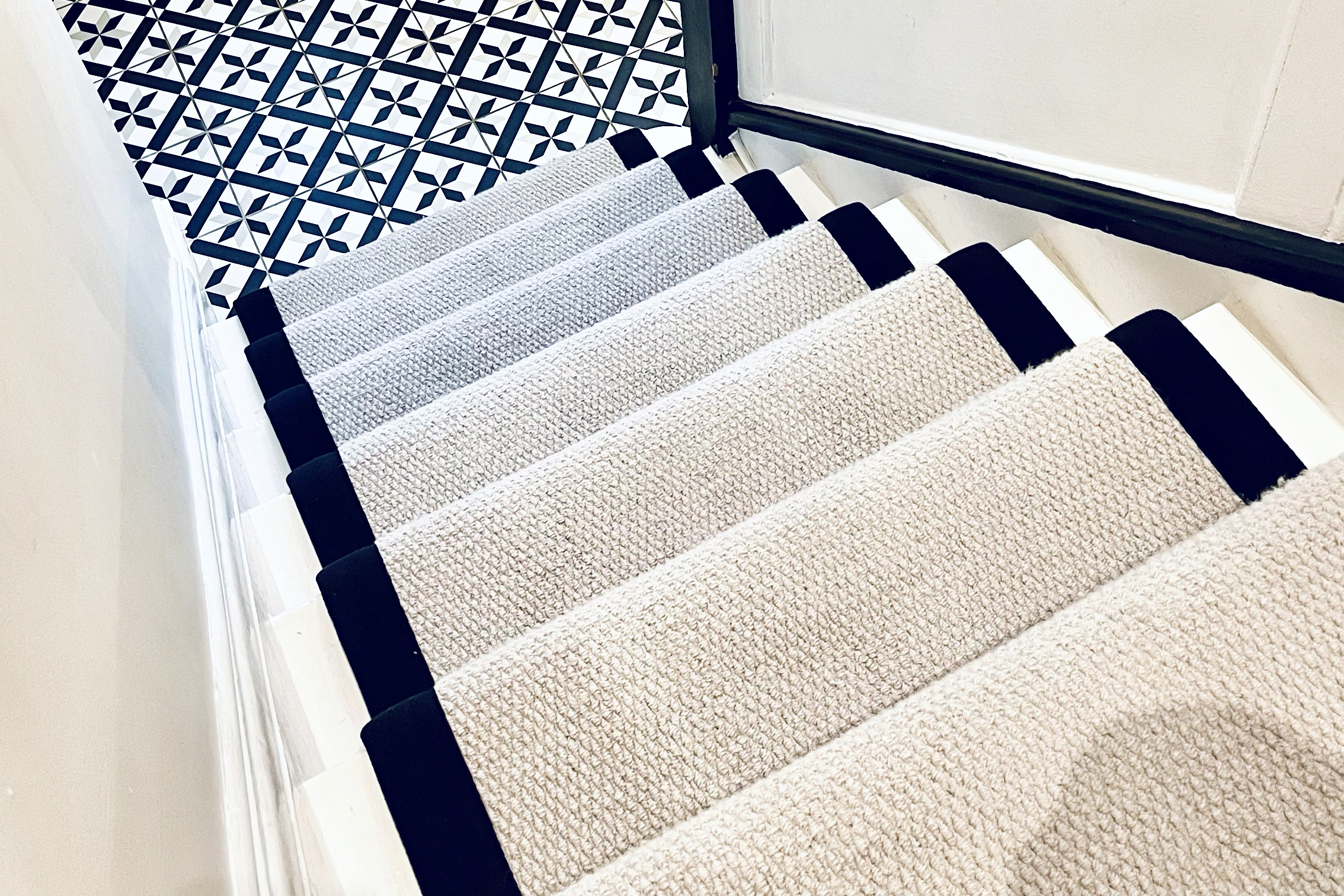 black and white tiled hallway with cream and black stair runner